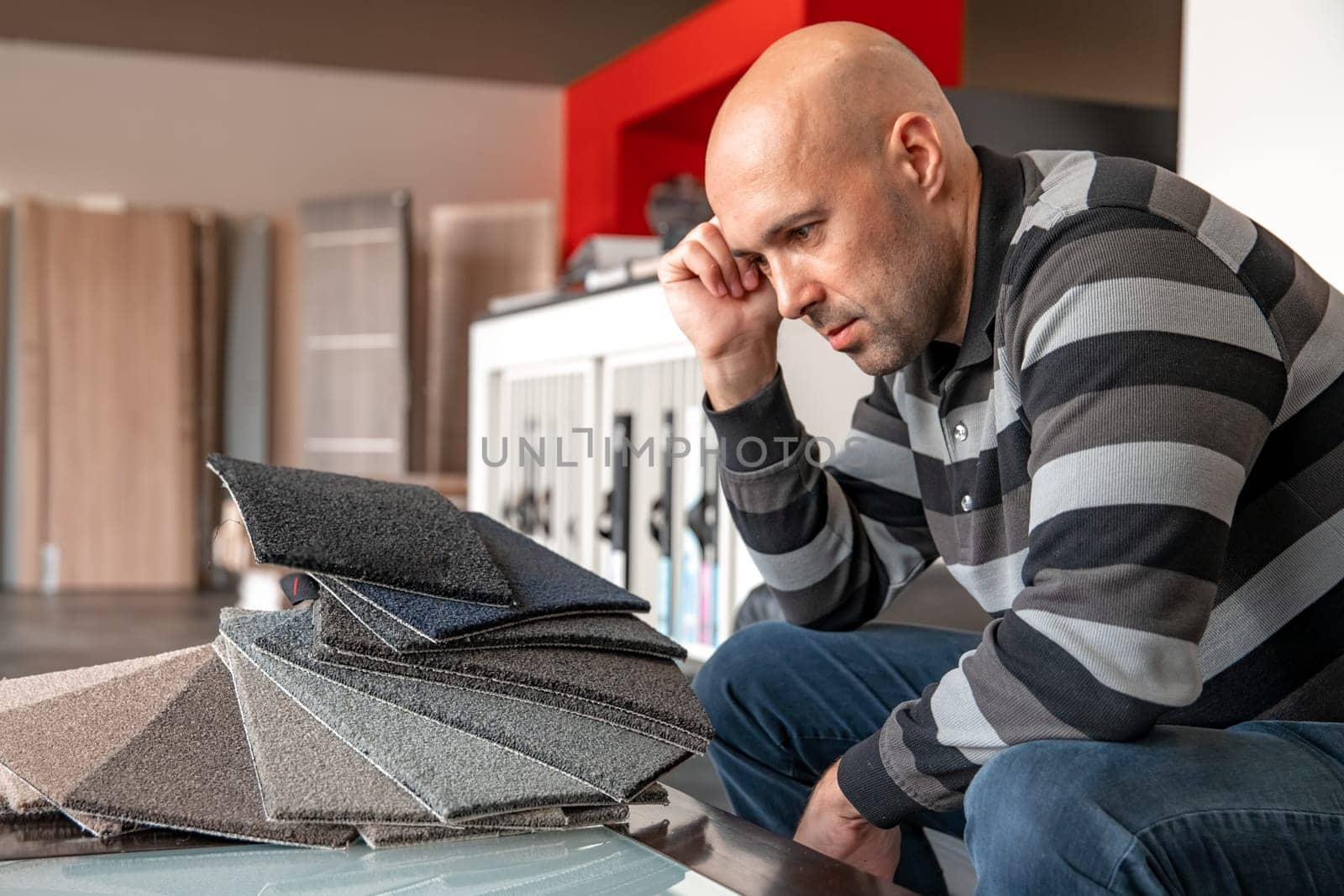 the man chooses the color of the new carpet according to the pattern book in the flooring shop.