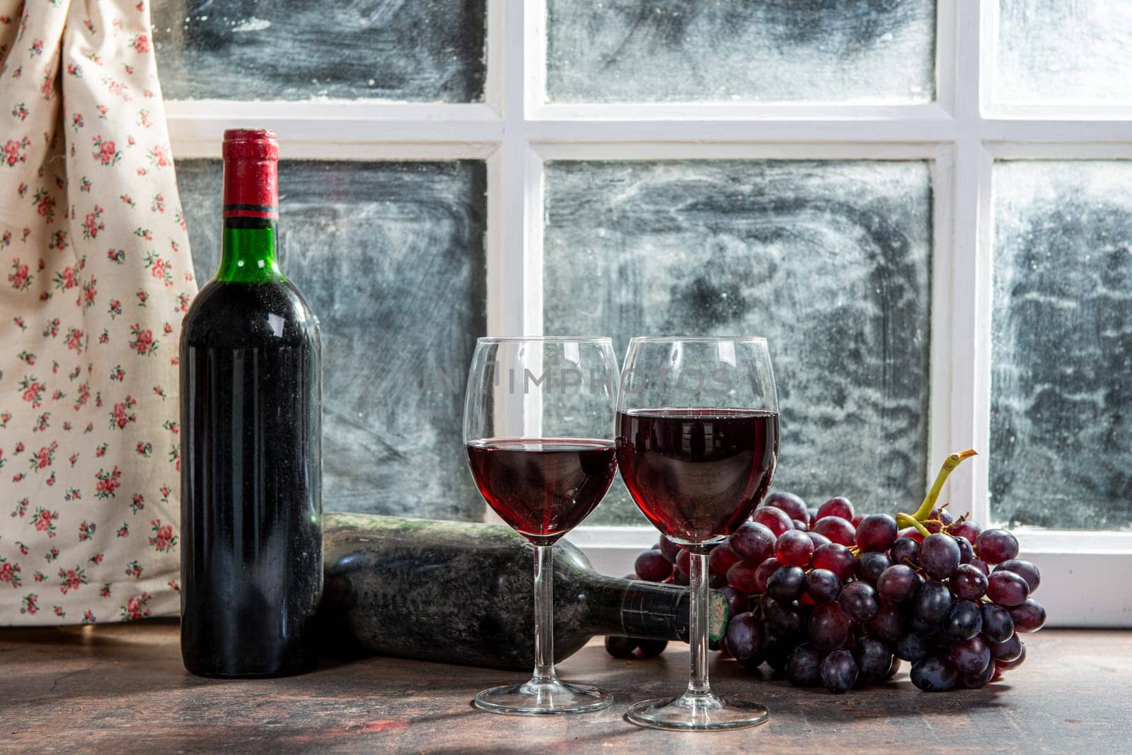 Composition with two wineglasses, grapes and bottles of red wine