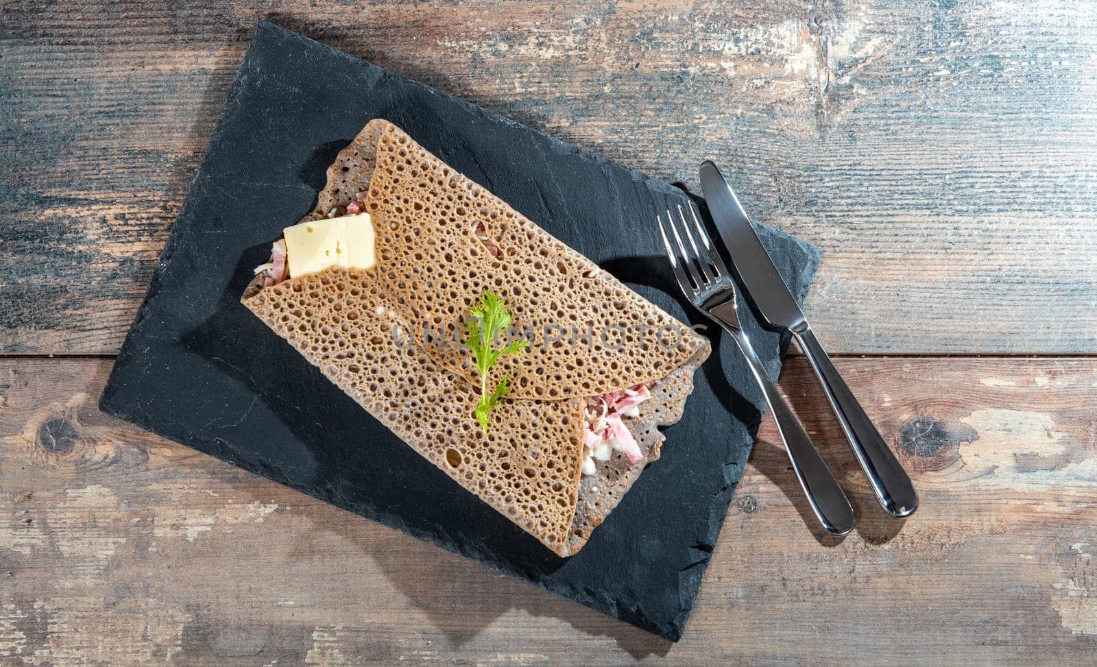 Breton crepe with cheese and bacon on a black slate