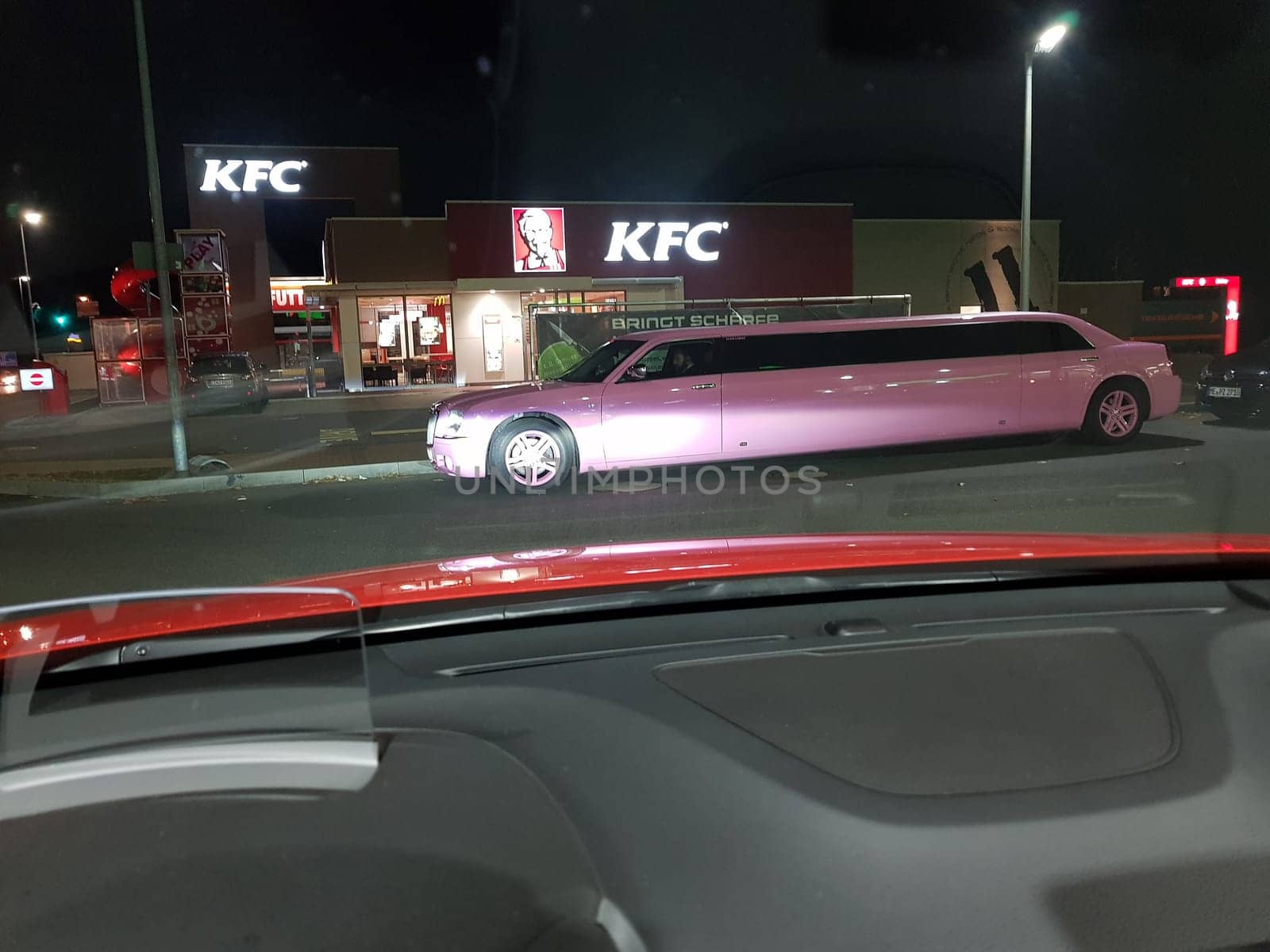 VELBERT, NRW, GERMANY - NOVEMBER 17, 2018:.A pink stretch limousine waits for the arrival of passengers in front of a Kentucky Fried Chicken restaurant in Velbert. Luxury vehicles and stretch limousines