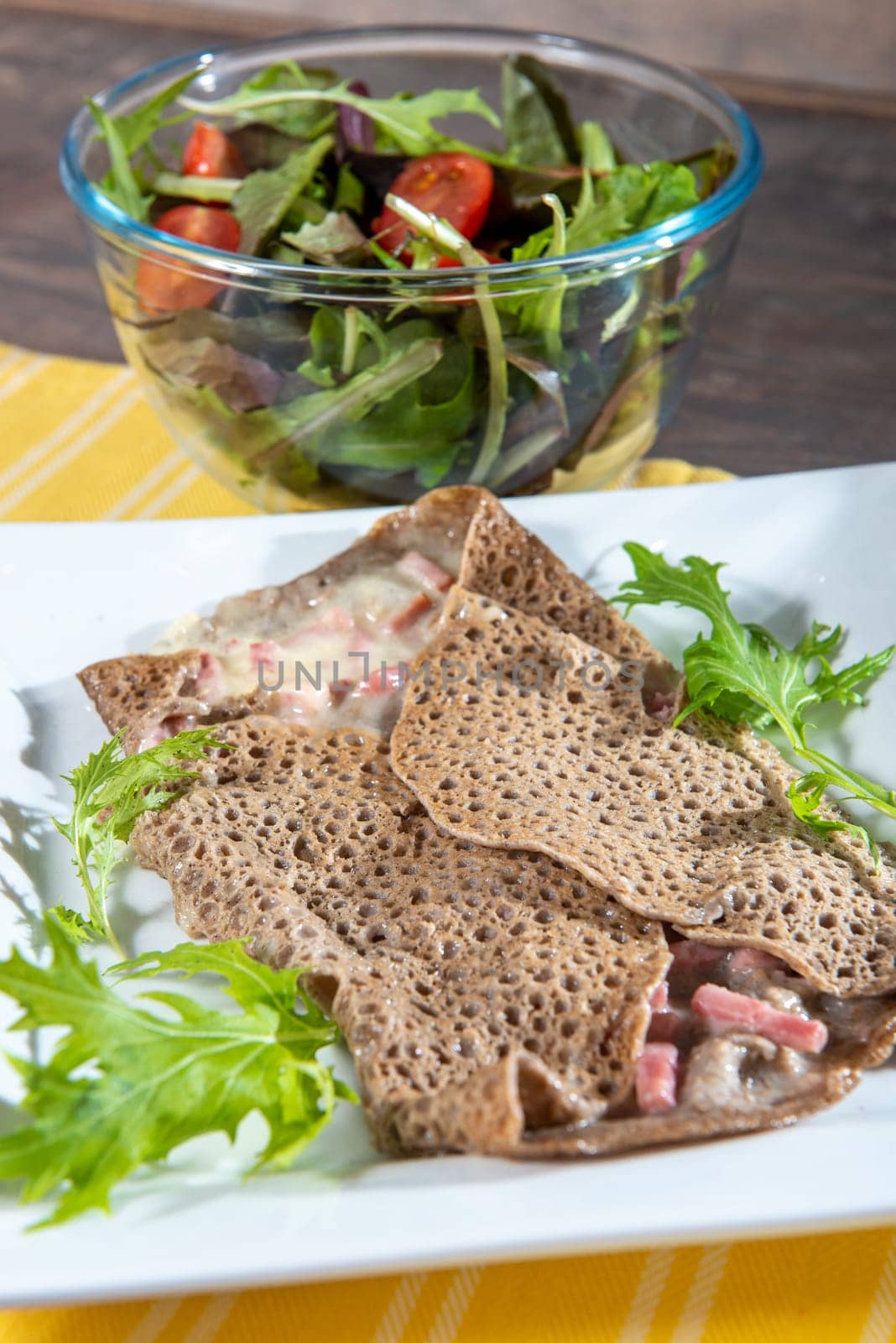Breton crepe with cheese and bacon in a white plate