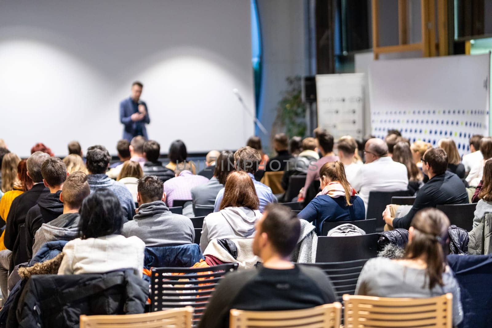 Speaker giving a talk in conference hall at business event. Rear view of unrecognizable people in audience at the conference hall. Business and entrepreneurship concept.