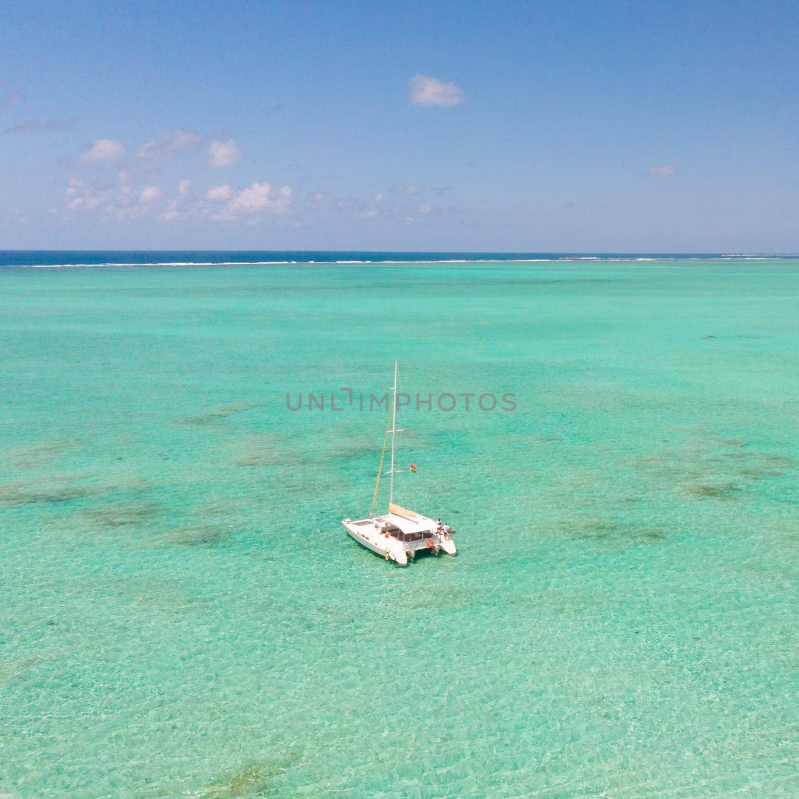 Catamaran sailing boat in turquoise sea lagoon on tropial Mauritius island. Aerial, top down drone view.