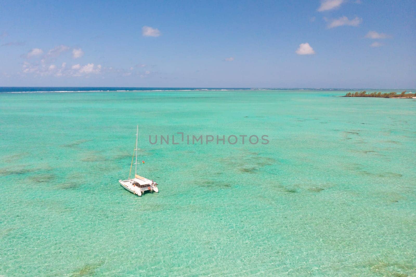 Catamaran sailing boat in turquoise sea lagoon on tropial Mauritius island. Aerial, top down drone view.