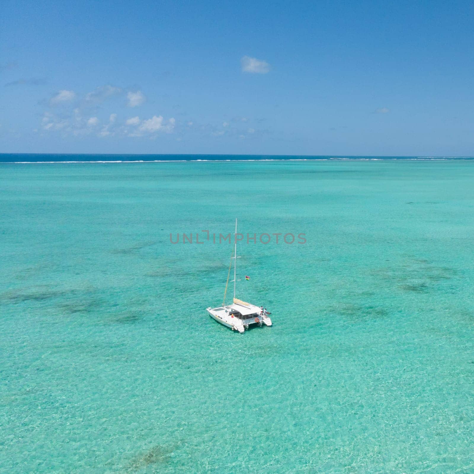 Catamaran sailing boat in turquoise sea lagoon on tropial Mauritius island. Aerial, top down drone view.