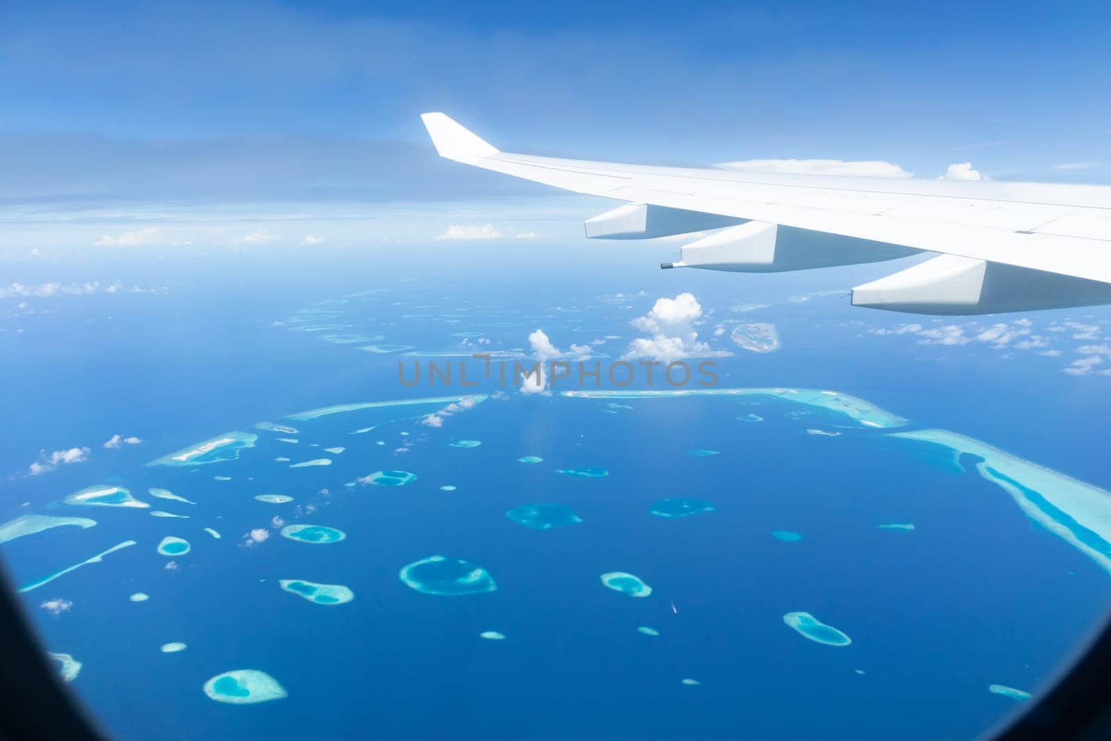 Top view of Maldive islands from airplane window with airplane's wing.