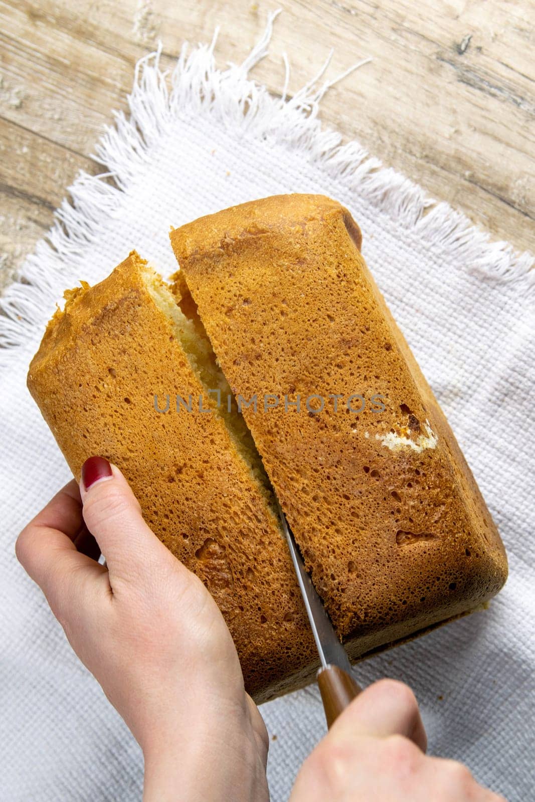 Fresh homemade bread stands on a white towel on a wooden board, next to a knife for cutting bread. Top views.