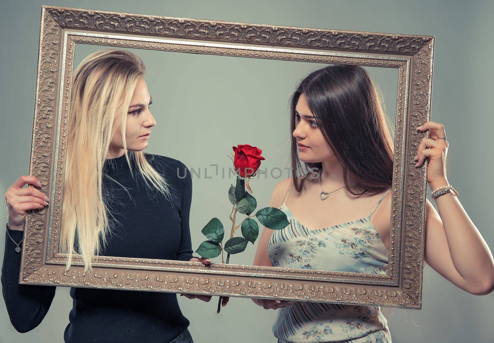 Portrait of two beautiful young women with a frame of image and roses