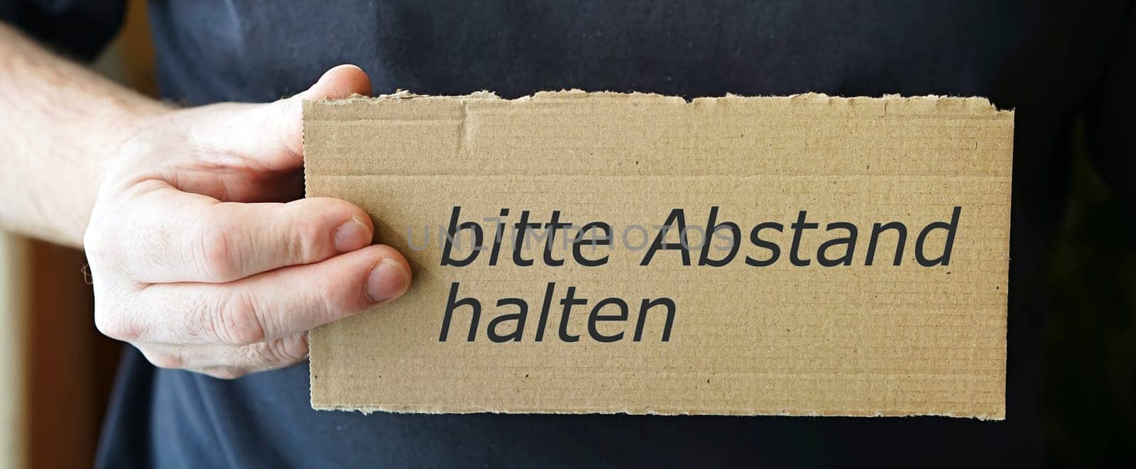 Cardboard sign with the inscription "please keep your distance"""
