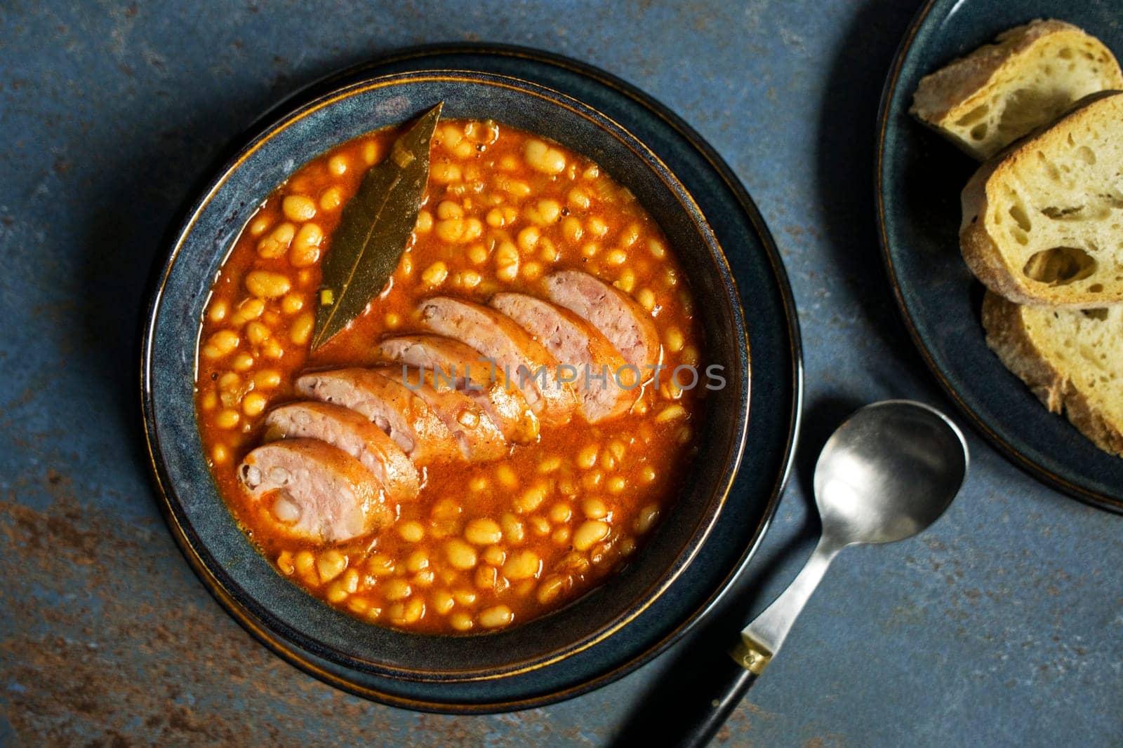 Baked beans stew with tomato sauce and sausage with herbs