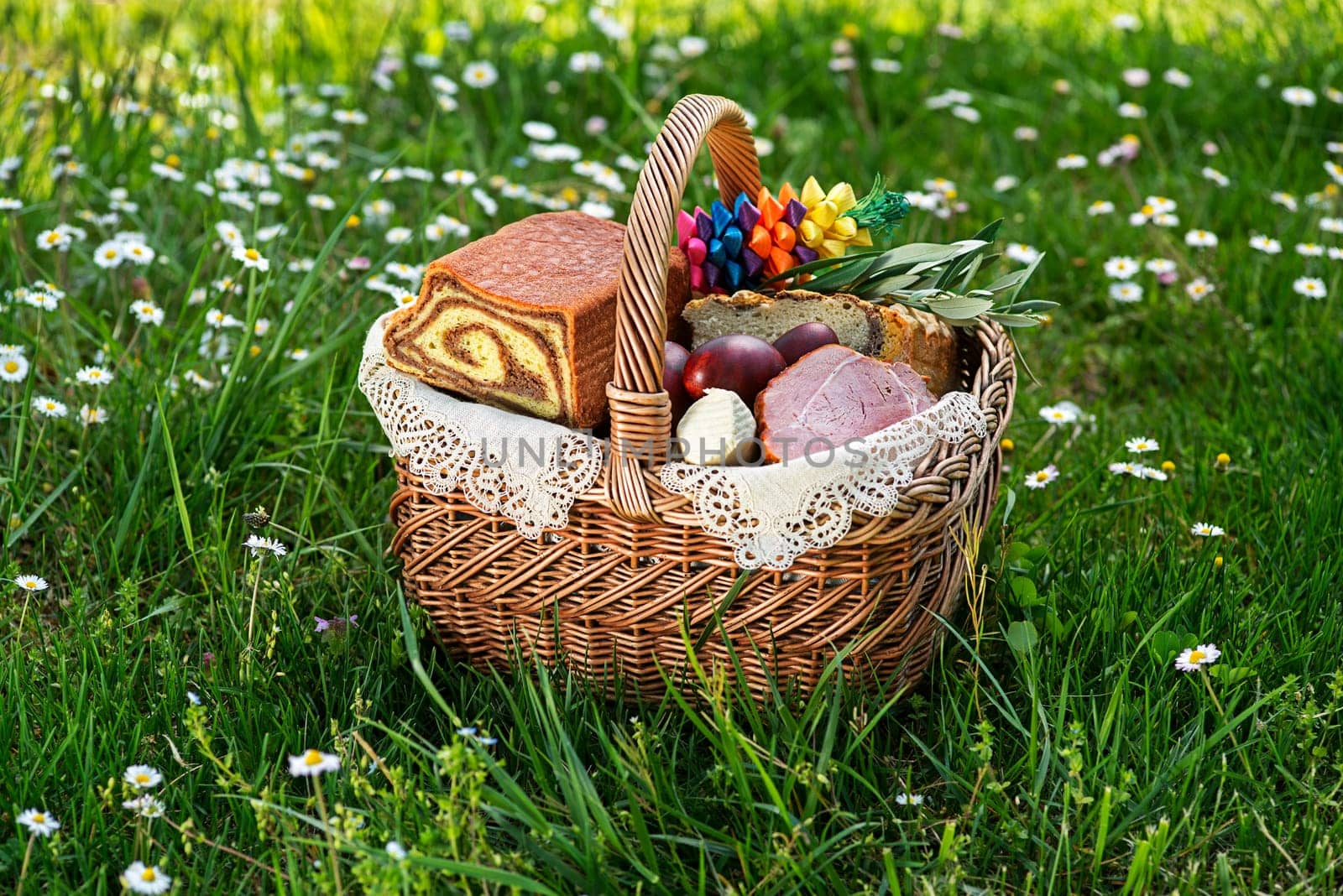 Easter traditional food with ham, eggs and bread in basket. Holidays background outdoor. Easter basket filled with all sorts of delicious delicatessen ready for an Easter meal.