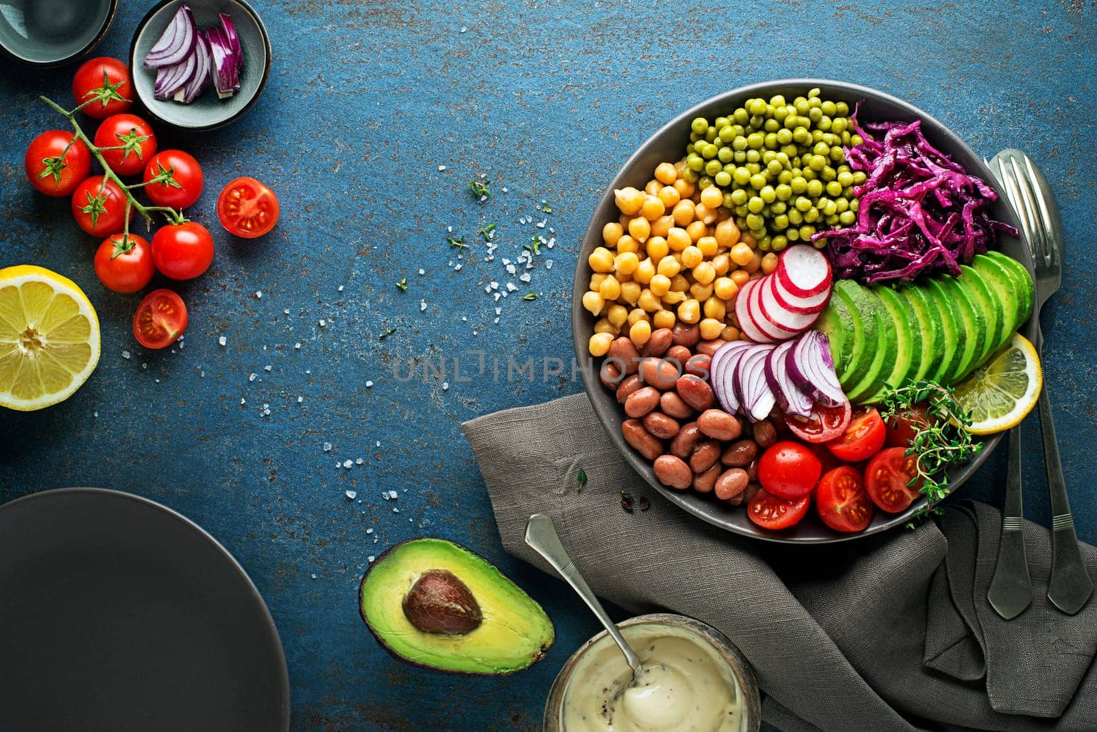 Healthy vegan lunch bowl. Avocado, chickpeas, tomato, red cabbage, green peas, red onion and radish vegetables salad. Healthy balanced vegetarian food concept Top view. Copy space