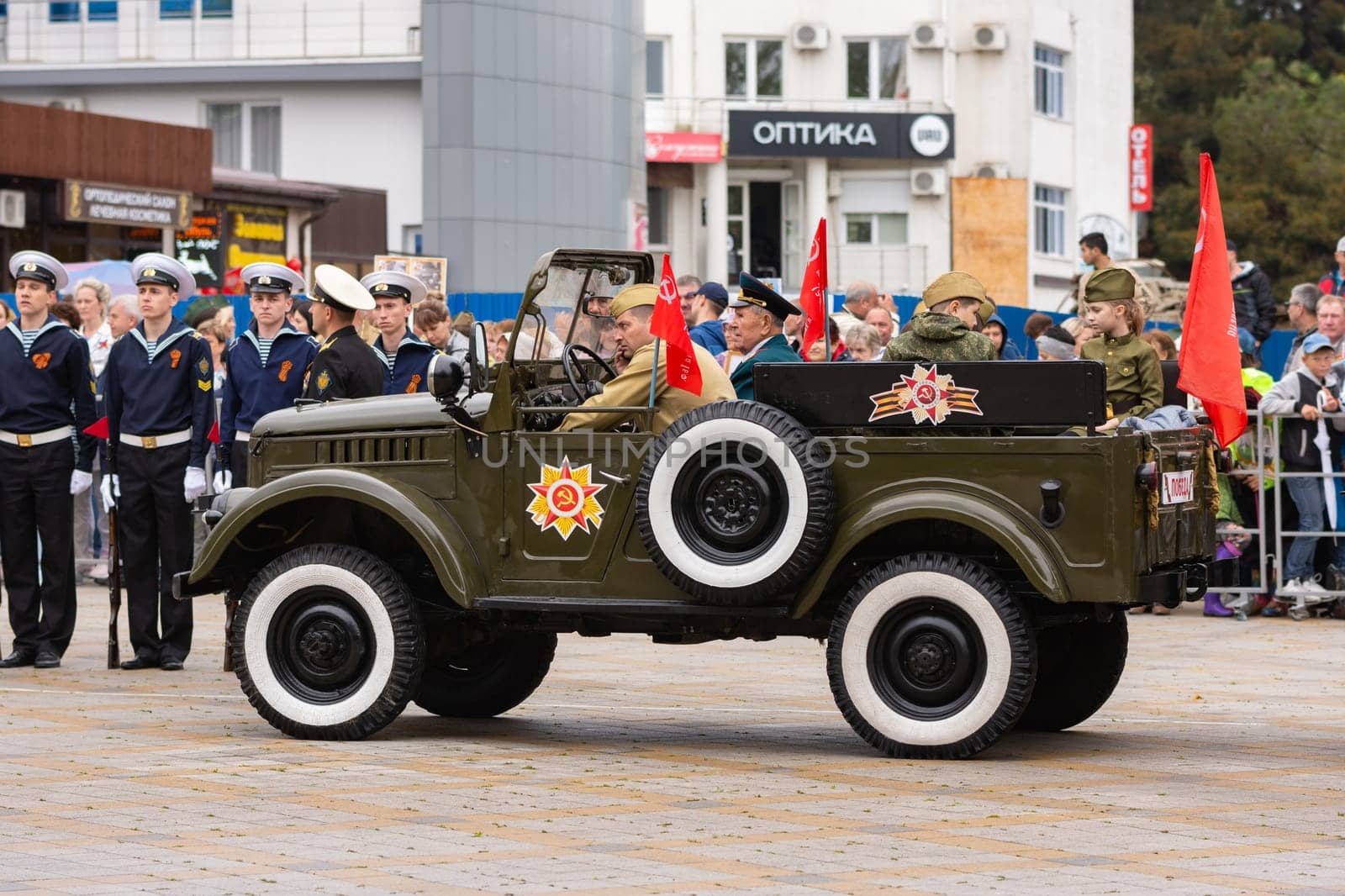 Anapa, Russia - May 9, 2019: A car with veterans and children awaits the start of the Victory Parade on Anapa Theater Square at Victory Day celebration