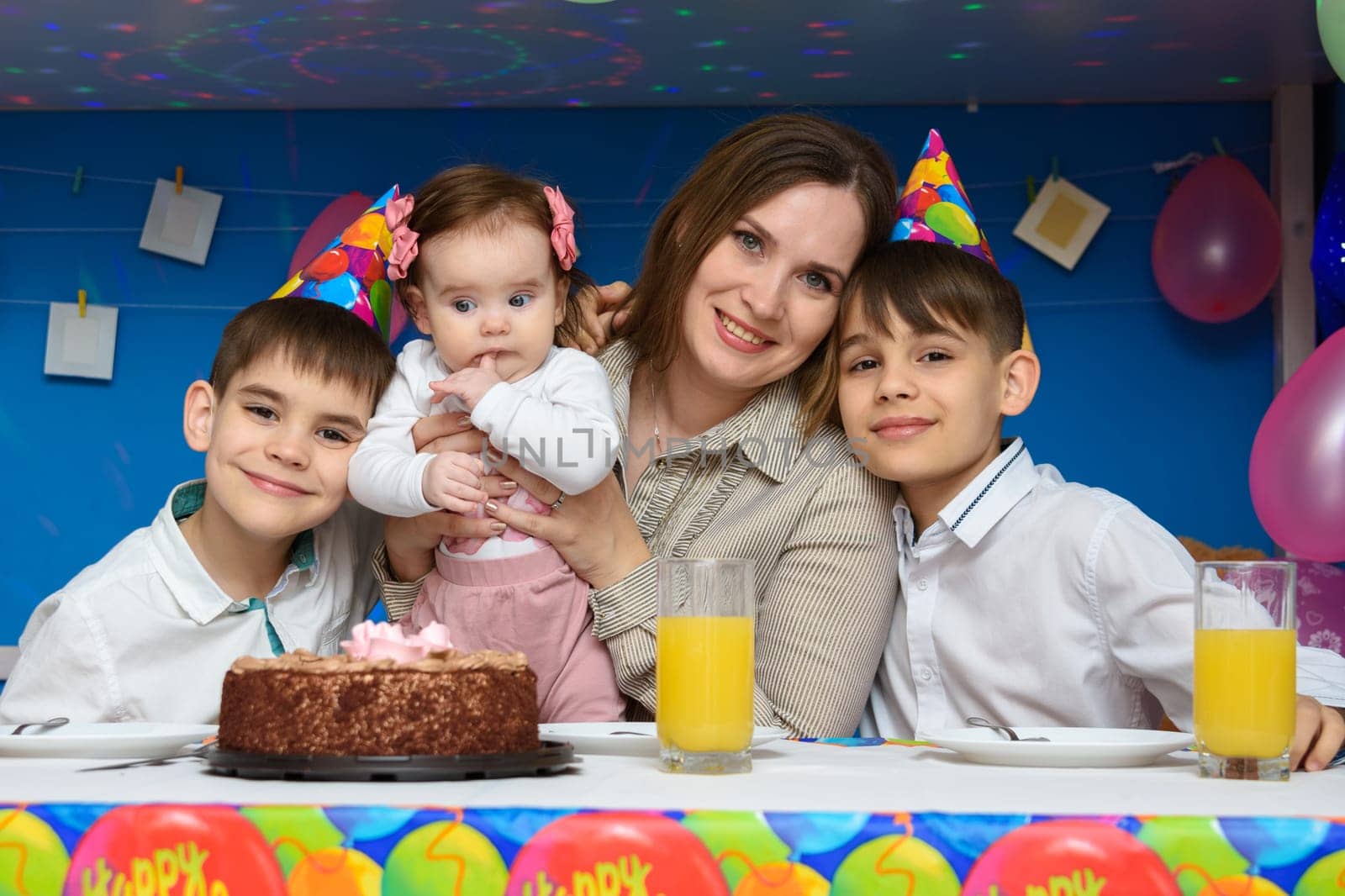 Mom, two sons and a baby daughter at the festive table in the home interior