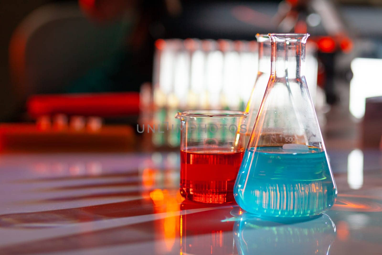 Illuminated laboratory flask filed with colorful chemical solutions with shadows on the table. Laboratory, science, reaserch, chemistry... consept.
