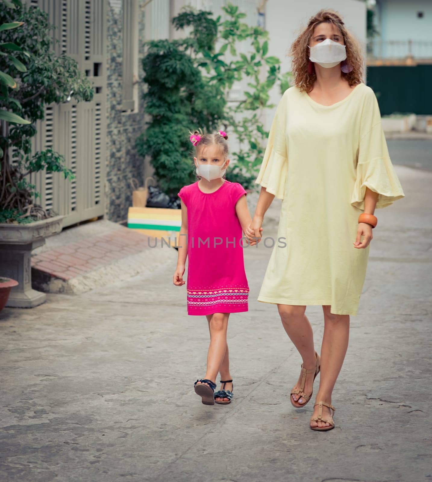Woman and daughter wearing facial disposable mask to avoid viral infection. Coronavirus protection