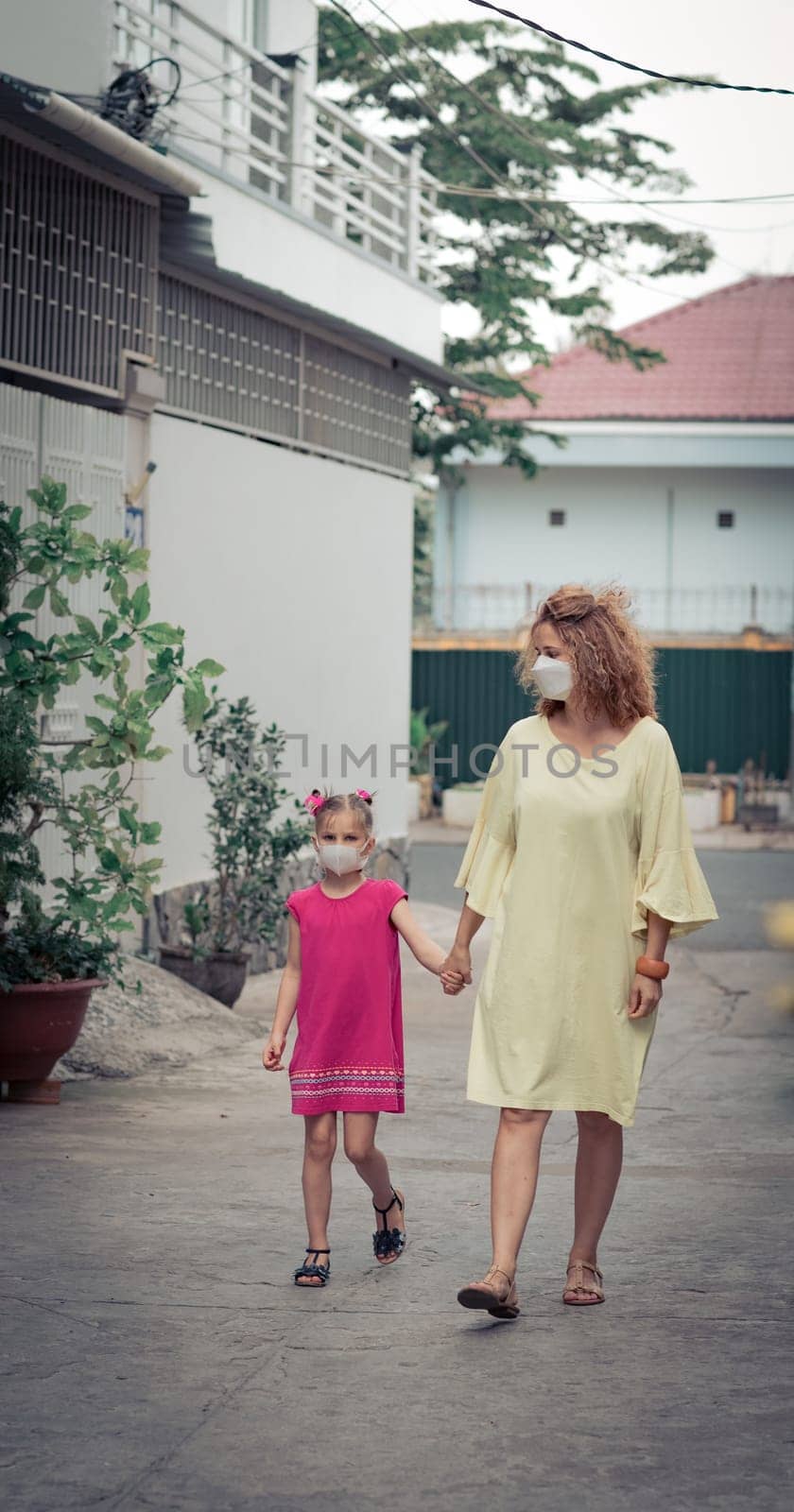 Woman and daughter wearing facial disposable mask to avoid viral infection. Coronavirus protection