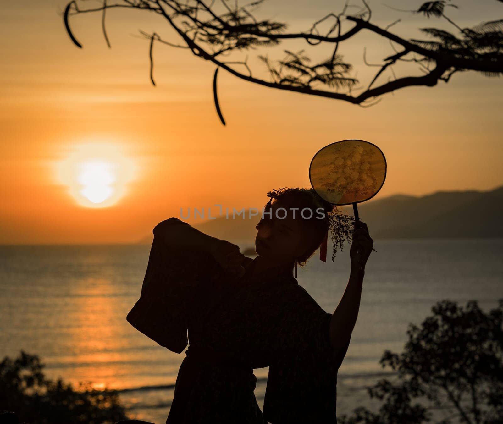Silhouette of Japanese Geisha in kimono with fan at sunrise