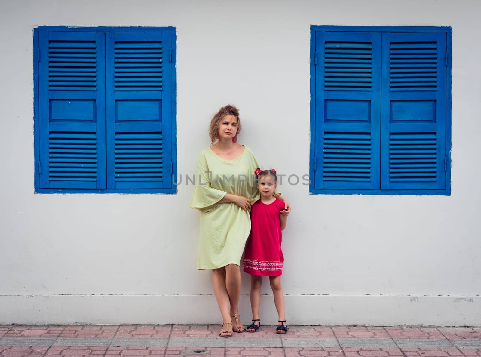 Mother and daughter next to shutter window in a street