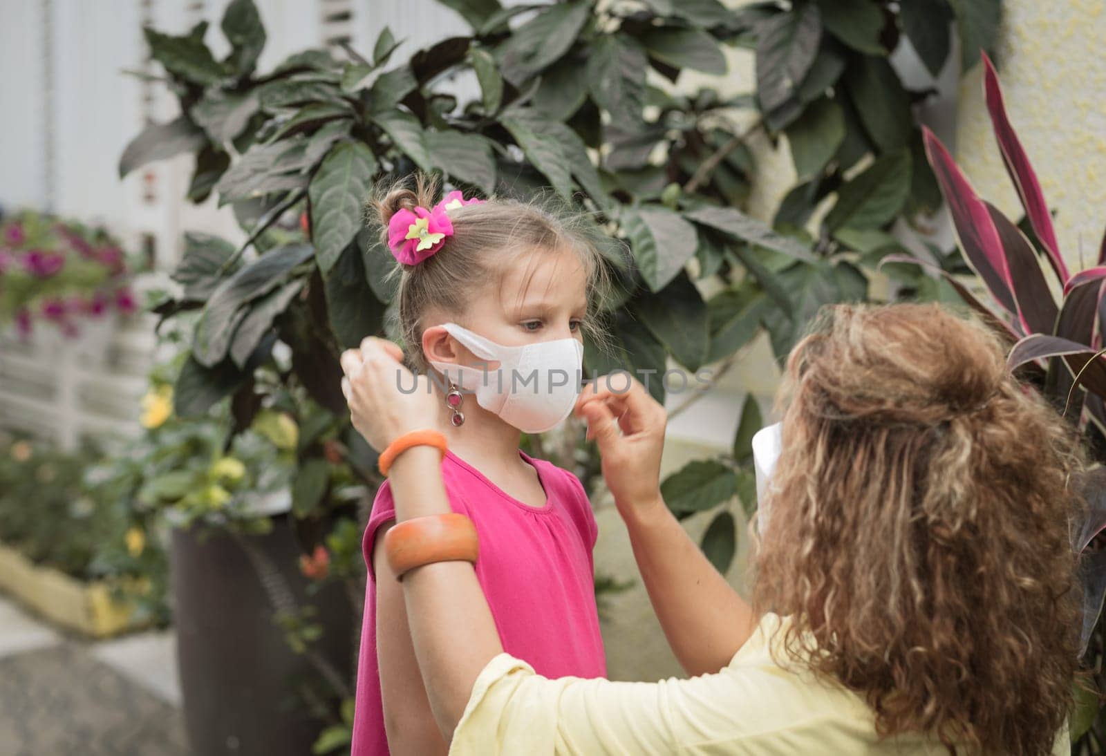 Woman and daughter wearing facial disposable mask to avoid viral infection. Coronavirus protection