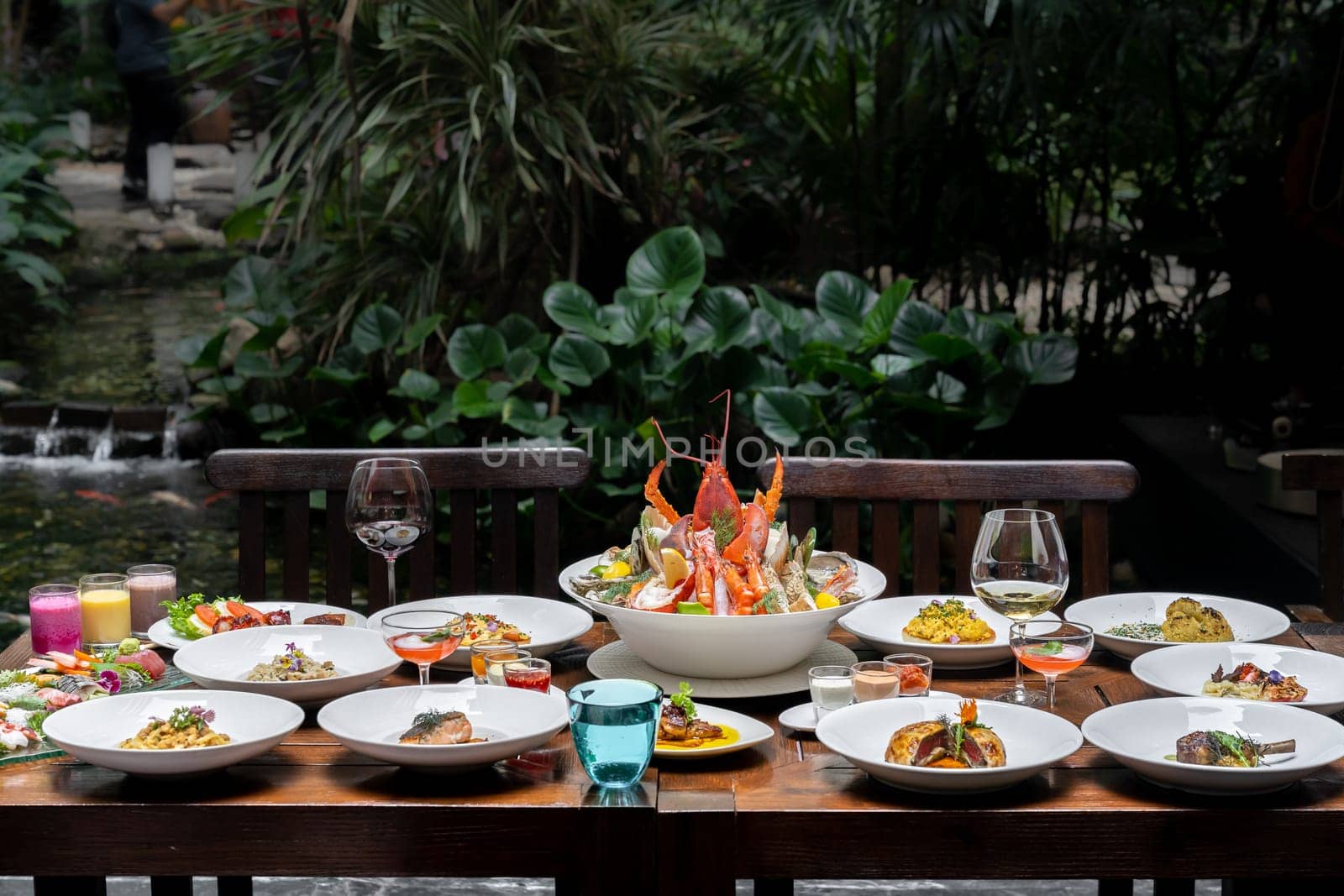Side view premium variety of international food in garden of restaurant of lobster shrimp steak beef lamb pasta spaghetti risotto rice sushi sashimi and wine using for buffet food drink background.
