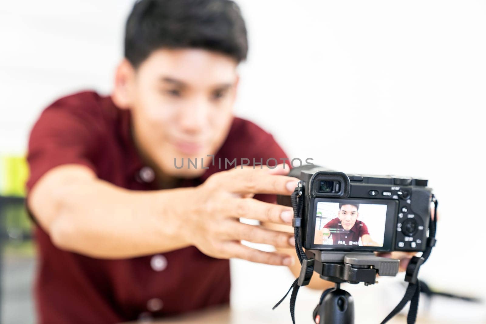 Young asian male blogger setting up camera for recording live vlog video tutorial session at home. IT blogging or vlogging, social media hobby broadcasting, or online learning course concept.