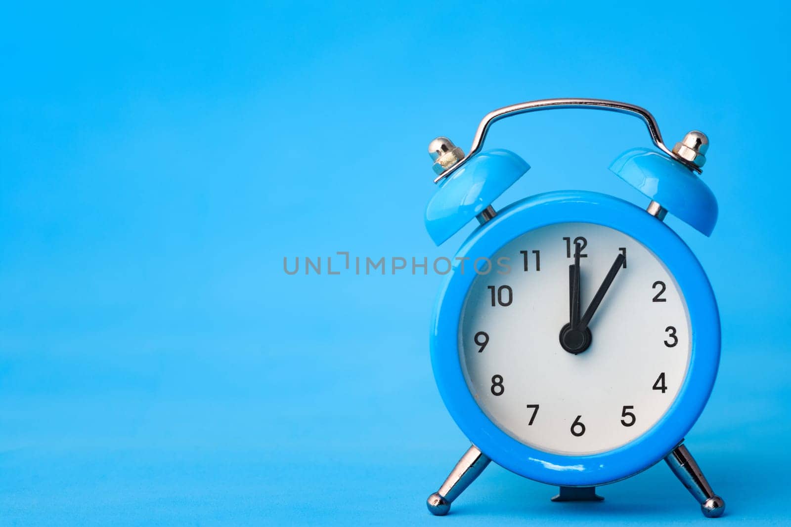 Alarm clock on a blue background, left empty space