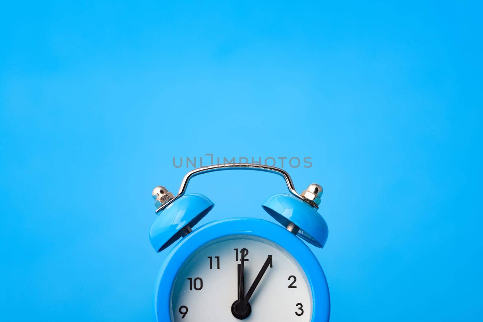 Fragment of an alarm clock and empty space above it, blue background