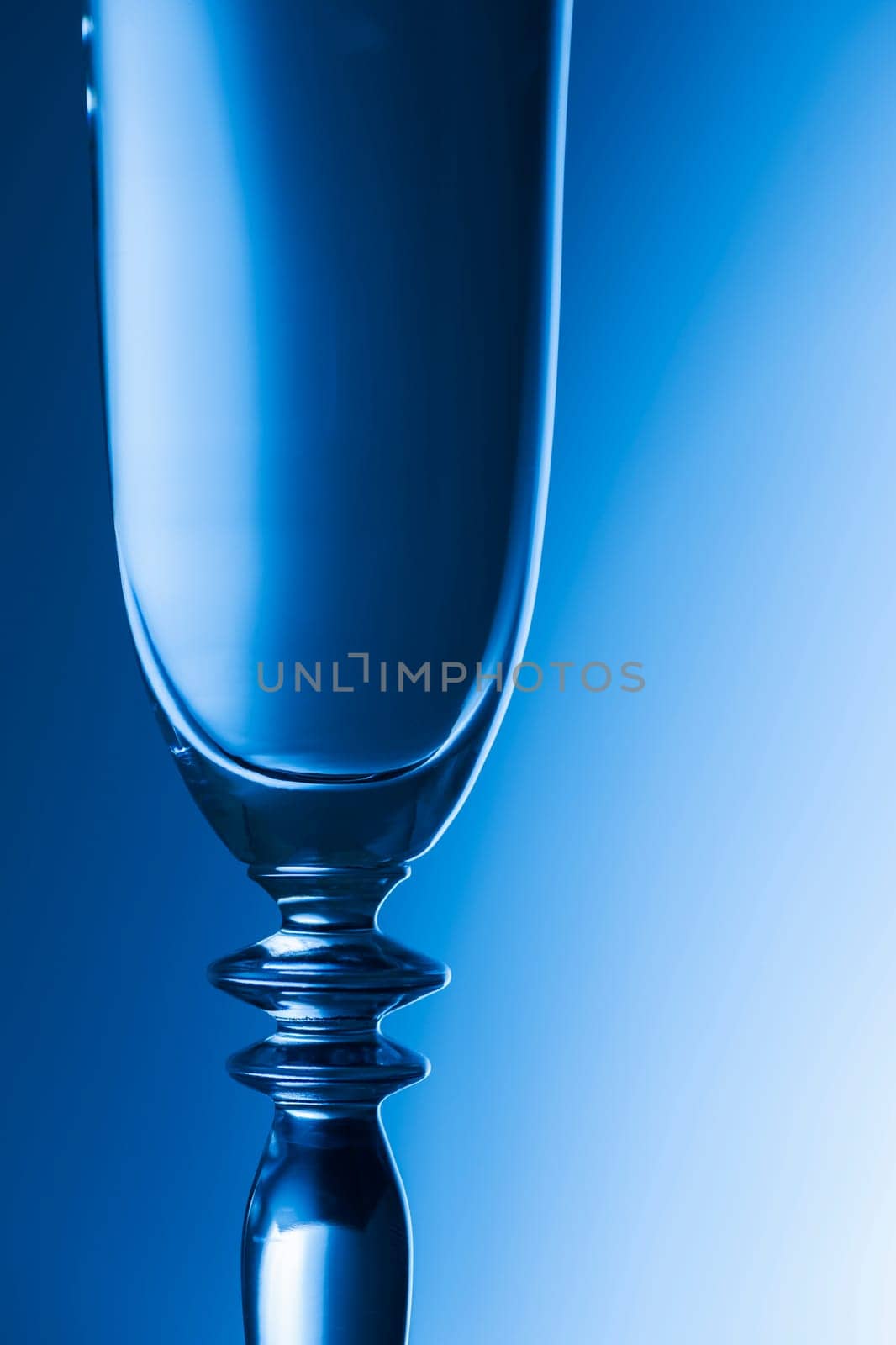 Upper part of a sparkling glass in front of a brightness-running background blue toned.