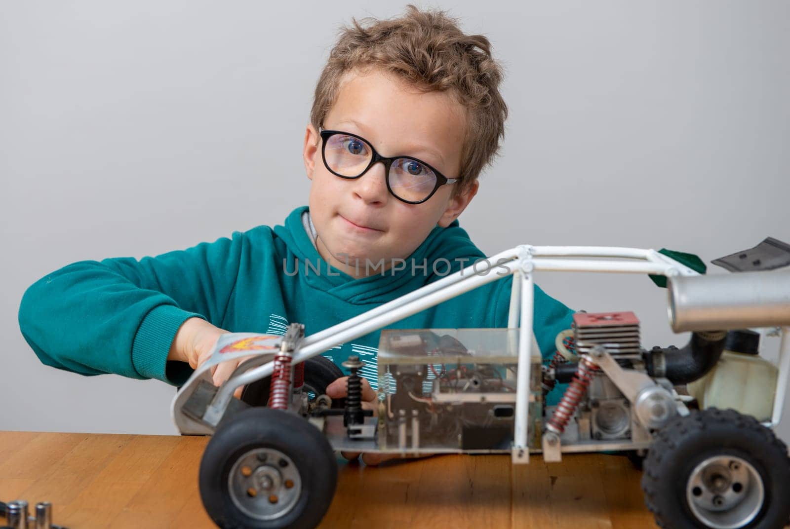 a little boy repairing a model radio-controlled car at home