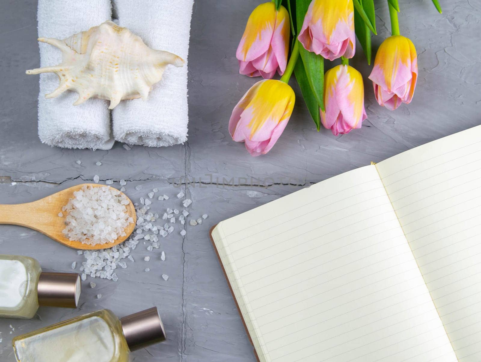 Spa with natural olive soap, tulips and sea salt and an open notebook for writing.