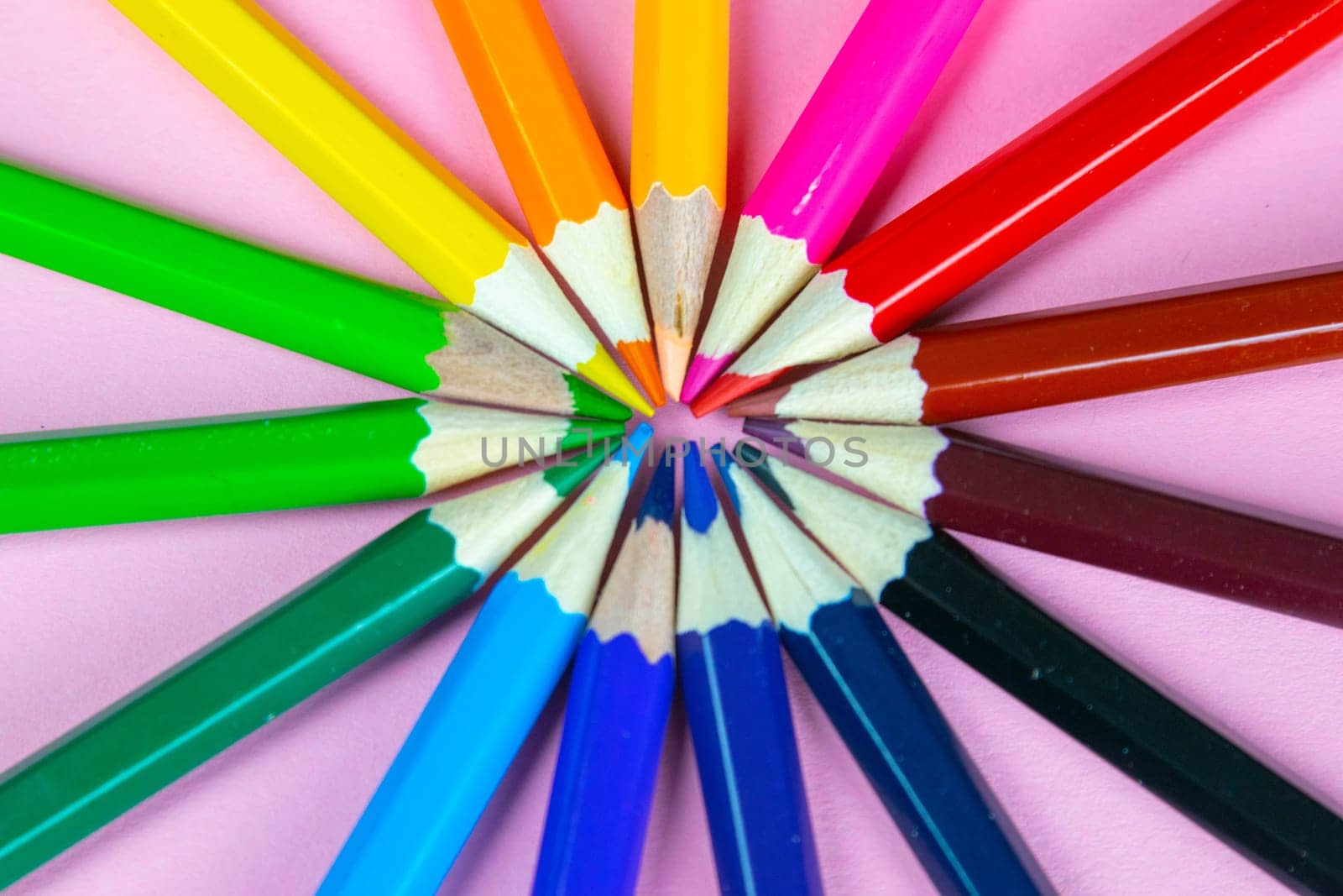 Color pencils on pink pastel background, close up. Set of colorful pencils. Crayons. Top view, flat lay. Back to school, college concept. Abstract background.