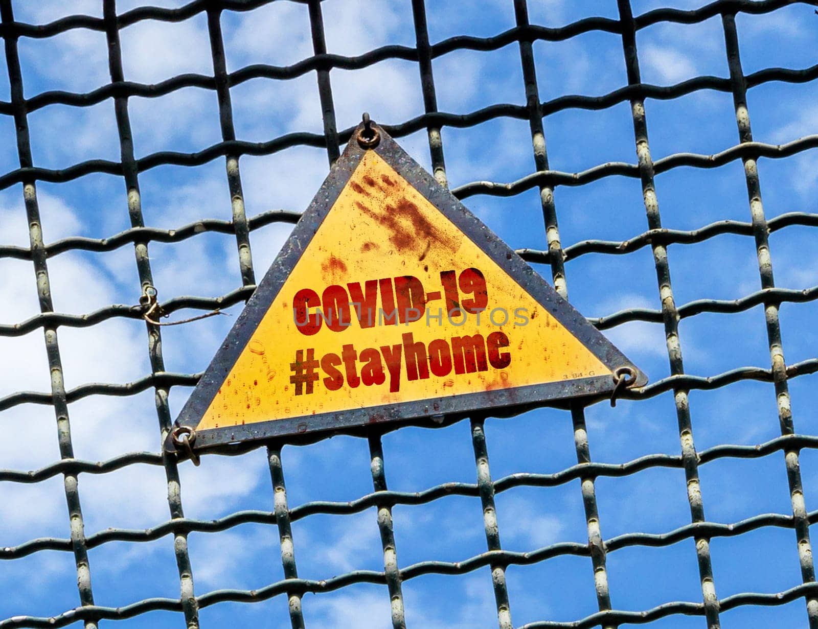 Warning sign with hashtag STAYHOME (COVID-19) placed on a metal fence. Coronavirus in the world. COVID-19 alert banner. 2019 Coronavirus concept, for an outbreak occurs in Wuhan - China.