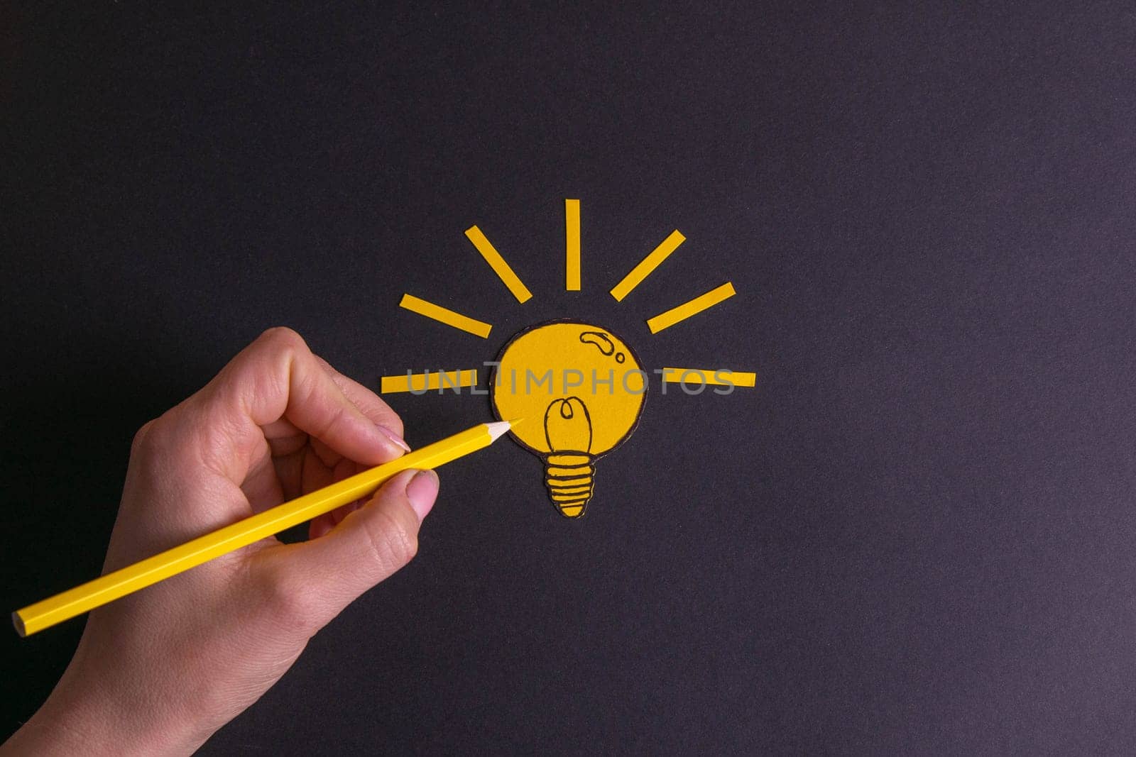 A yellow pencil in hand next to a creative painted light bulb. The concept of innovation and creative ideas/