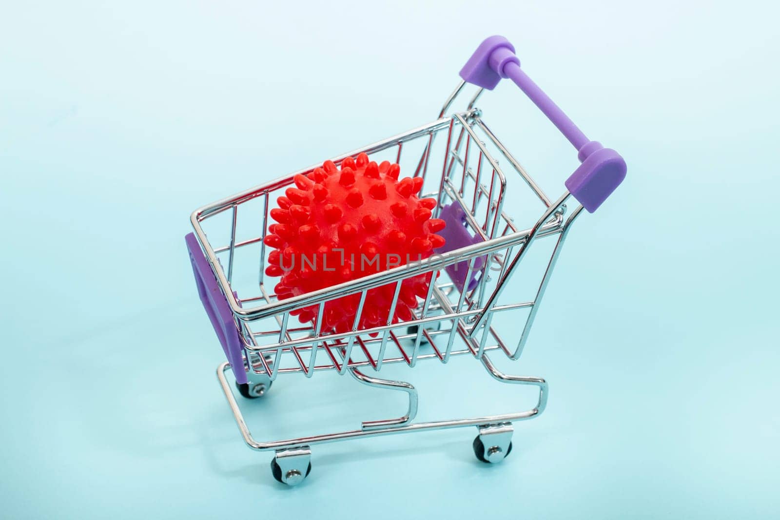 Virus in a miniature shopping cart isolated on a light blue background.