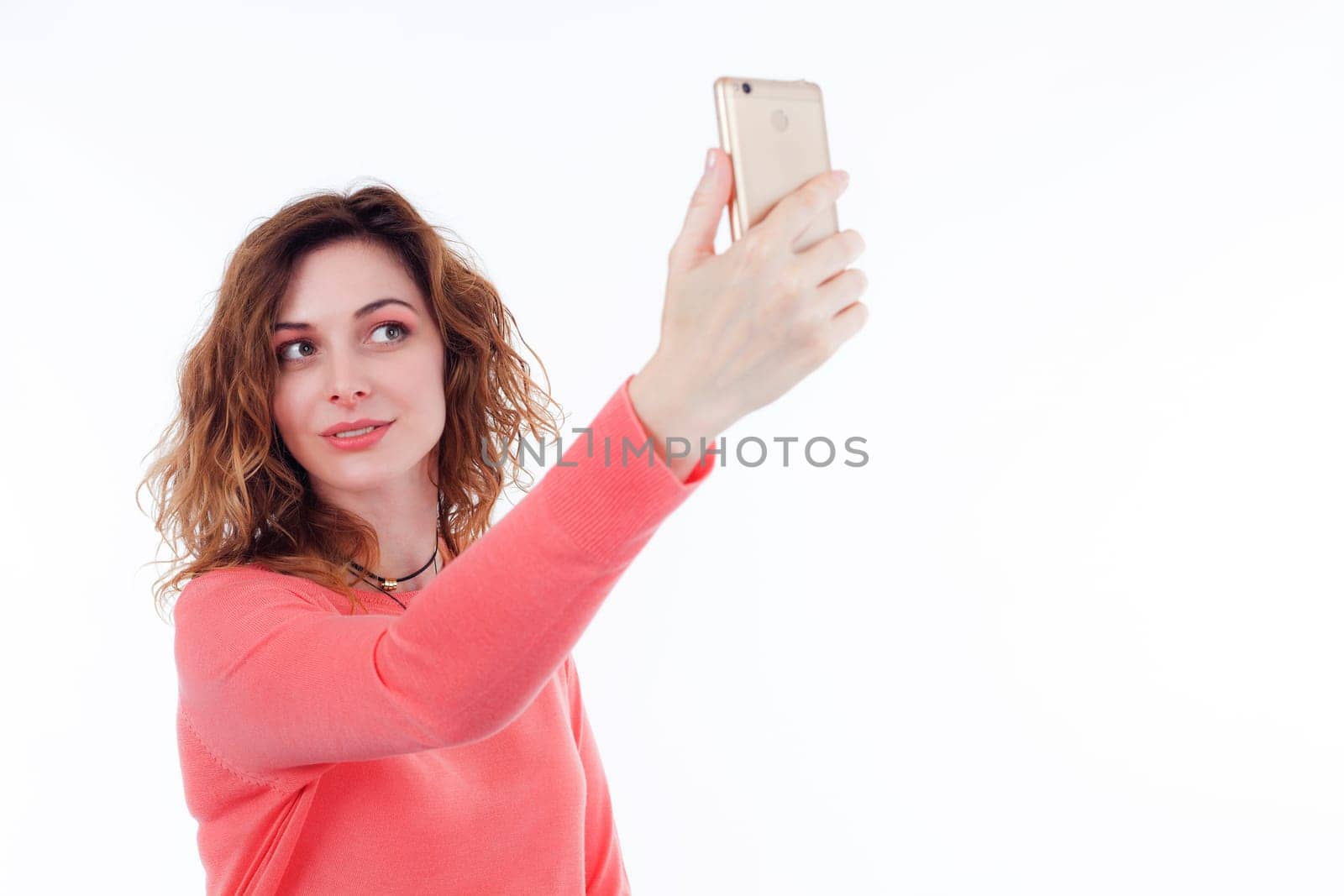 Portrait of cute joyful woman with trendy hairstyle wearing basic t-shirt talking on mobile phone isolated over white background.