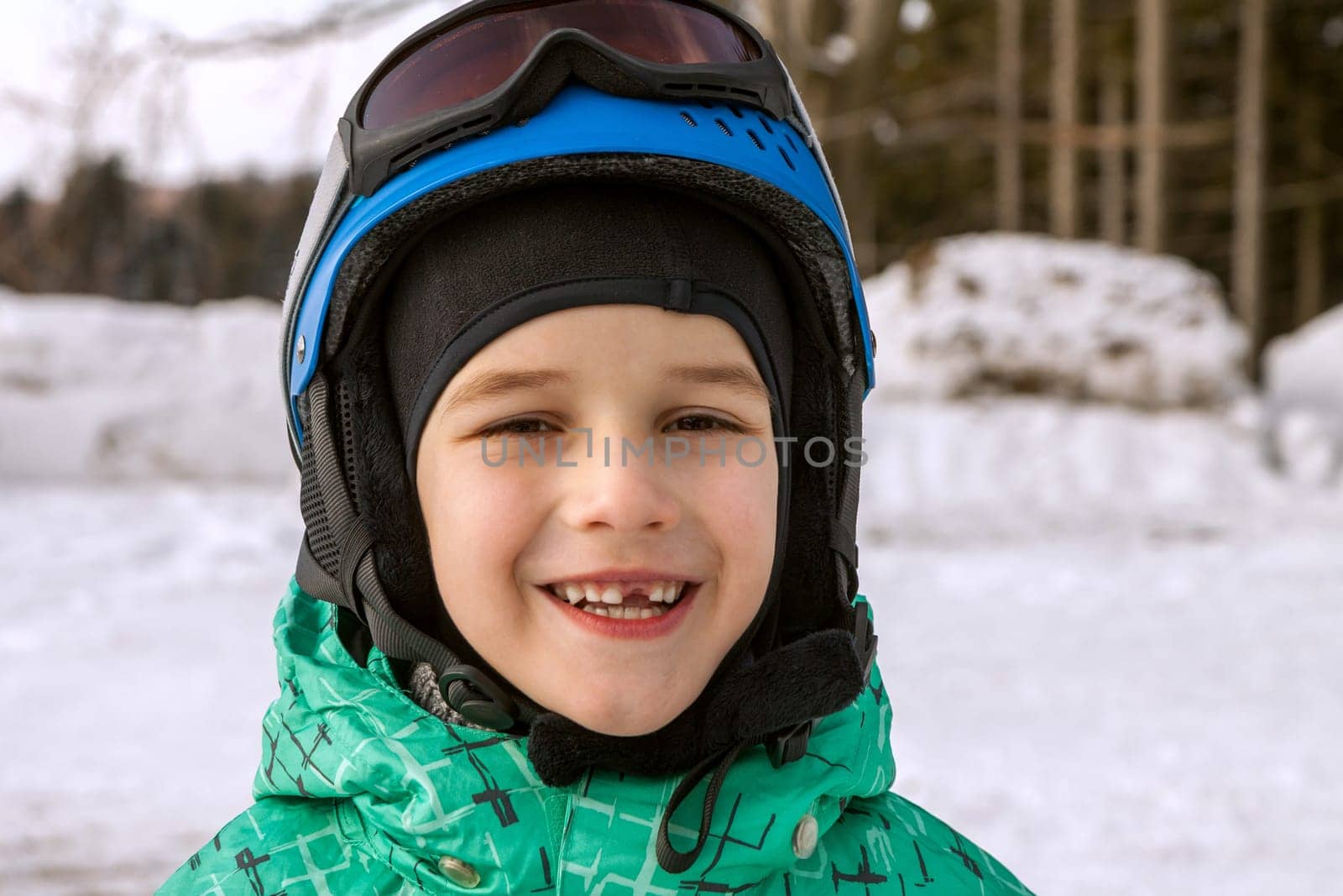 little boy on mountains in ski helmet with fallen first tooth, Czech Republic