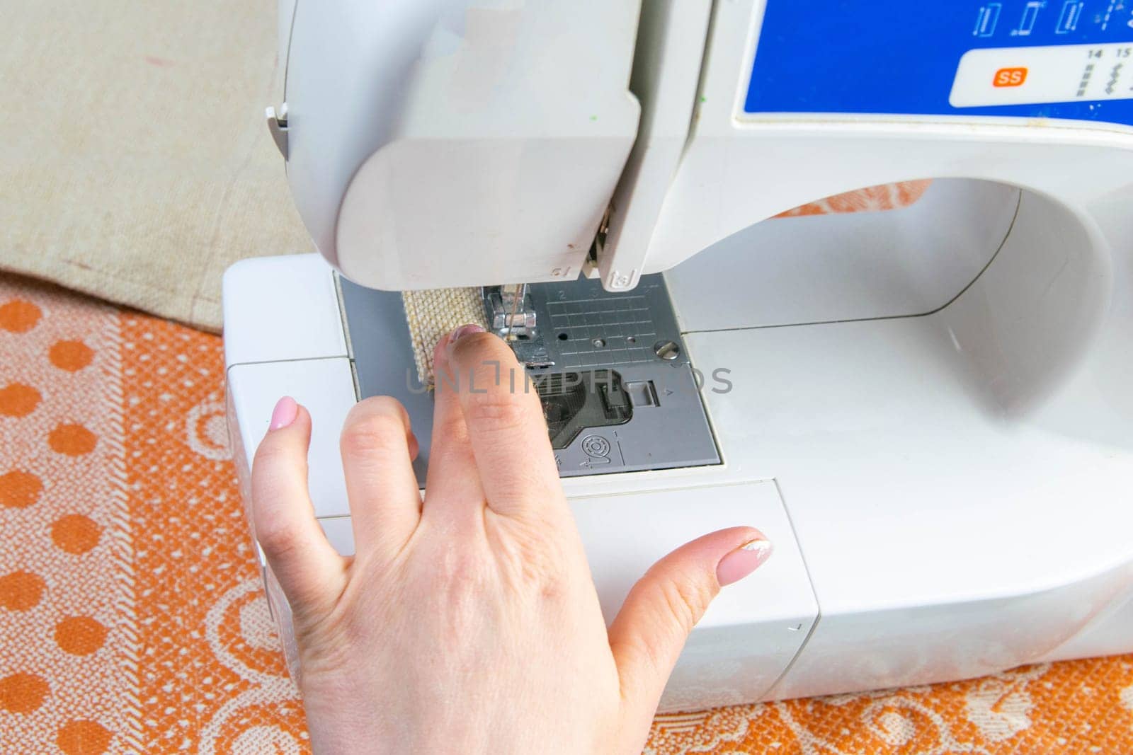 Female hands work on a sewing machine, sewing coffee towel. Close-up.