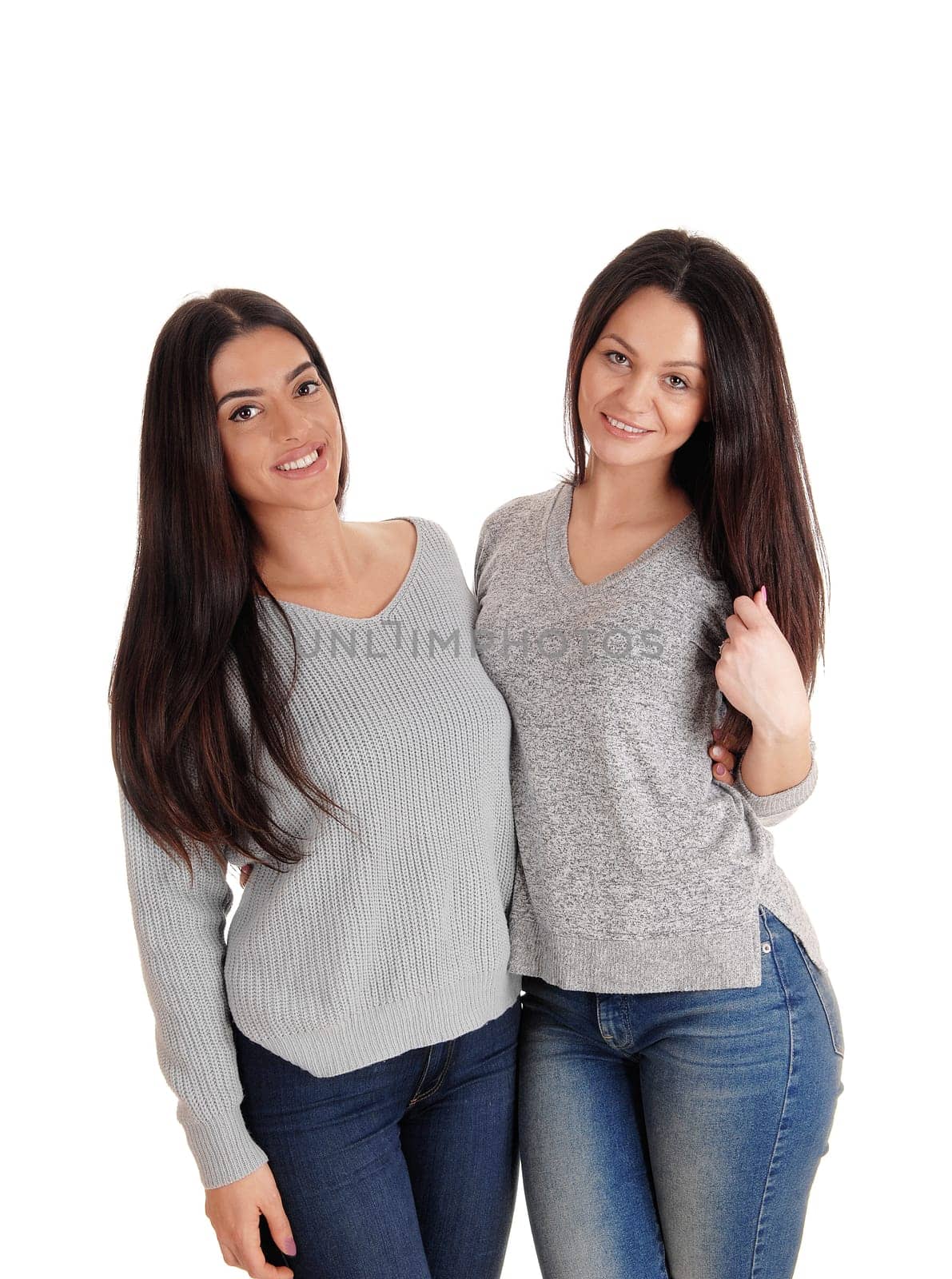 Two beautiful young woman standing site to site in jeans .looking at the camera, isolated for white background.
