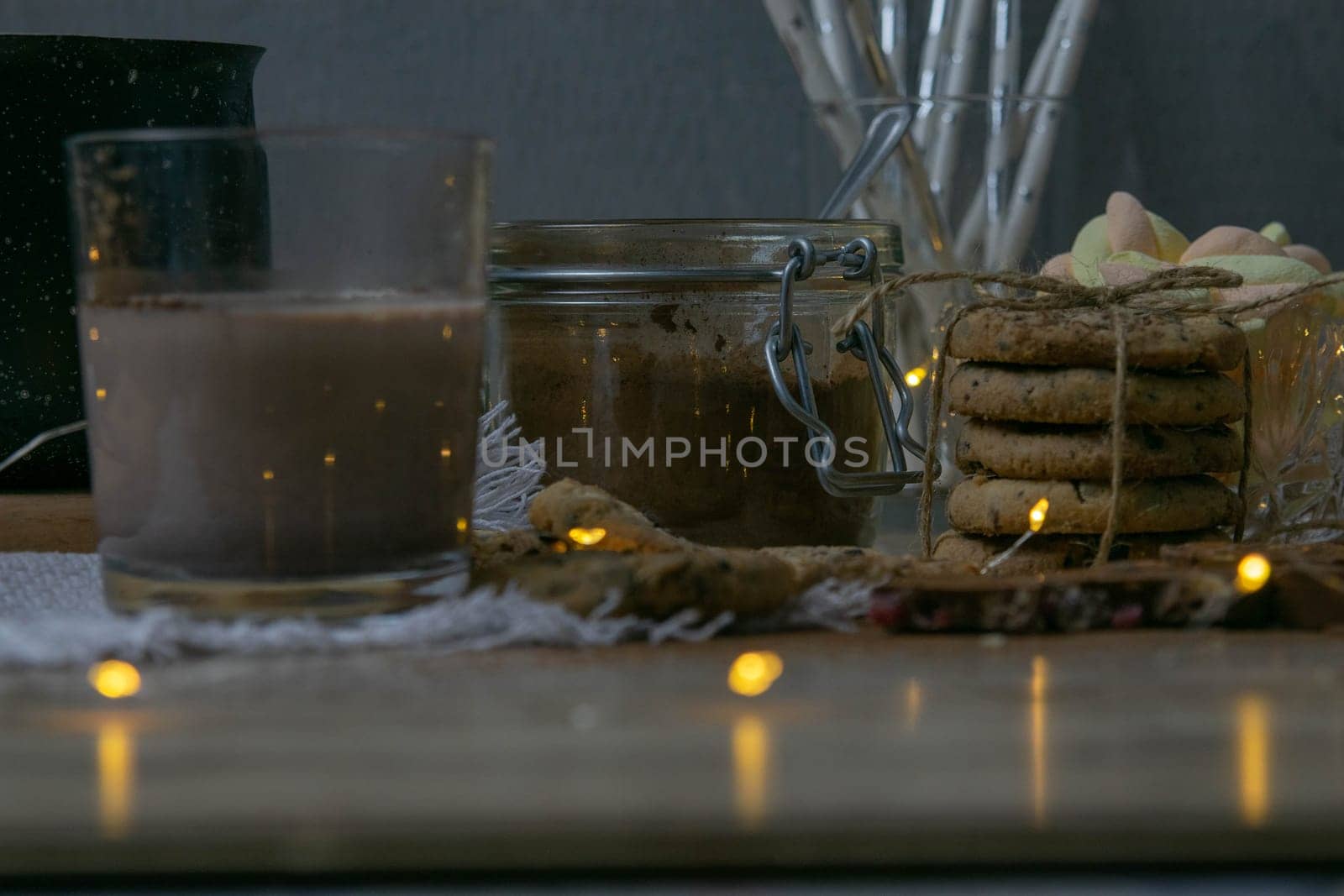 Cocoa with marshmallows and chocolate oven and slices of chocolate stands on a wooden table.