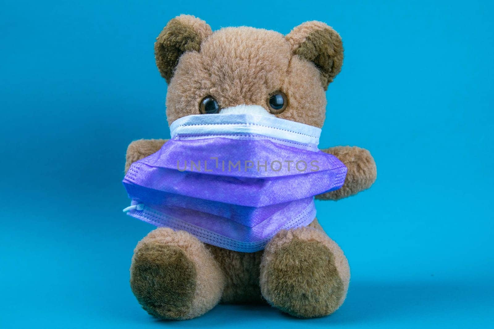 big teddy bear are sitting in blue medical masks on a blue background, concept of protection from respiratory disease, virus, and individual respiratory protection.