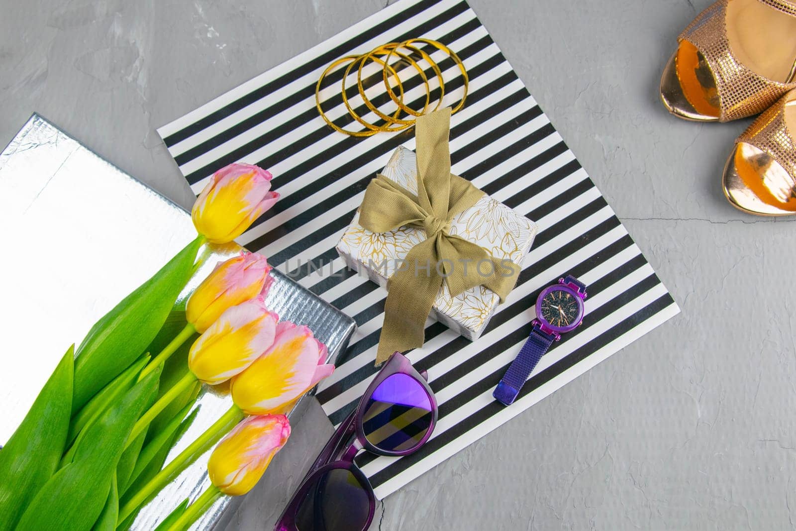 Tulips with a gift on a striped background along with glasses and watches.