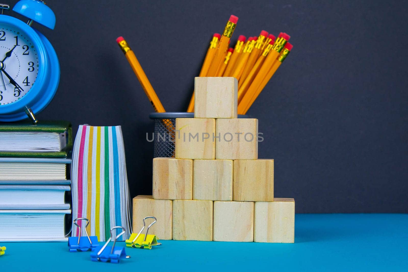 The globe and the clock stand on a stack of books, next to a glass of pencils and the pyramid is folded with wooden cubes.