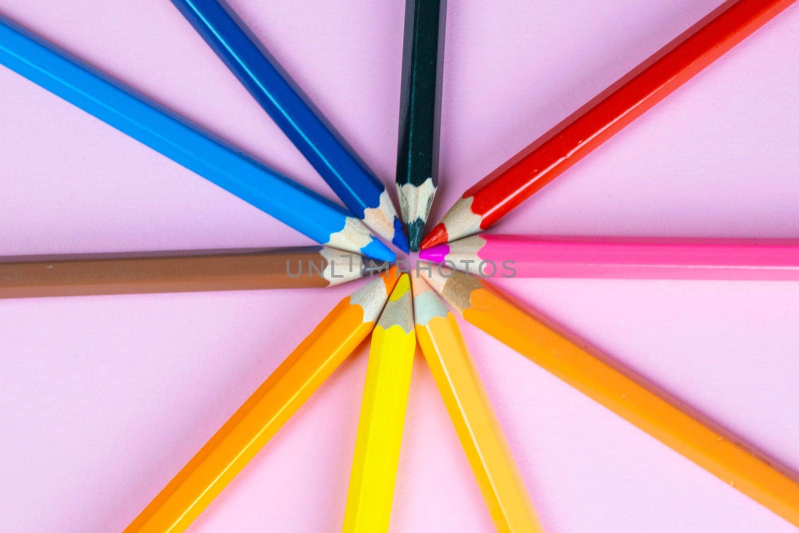 Color pencils on pink pastel background, close up. Set of colorful pencils. Crayons. Top view, flat lay. Back to school, college concept. Abstract background.