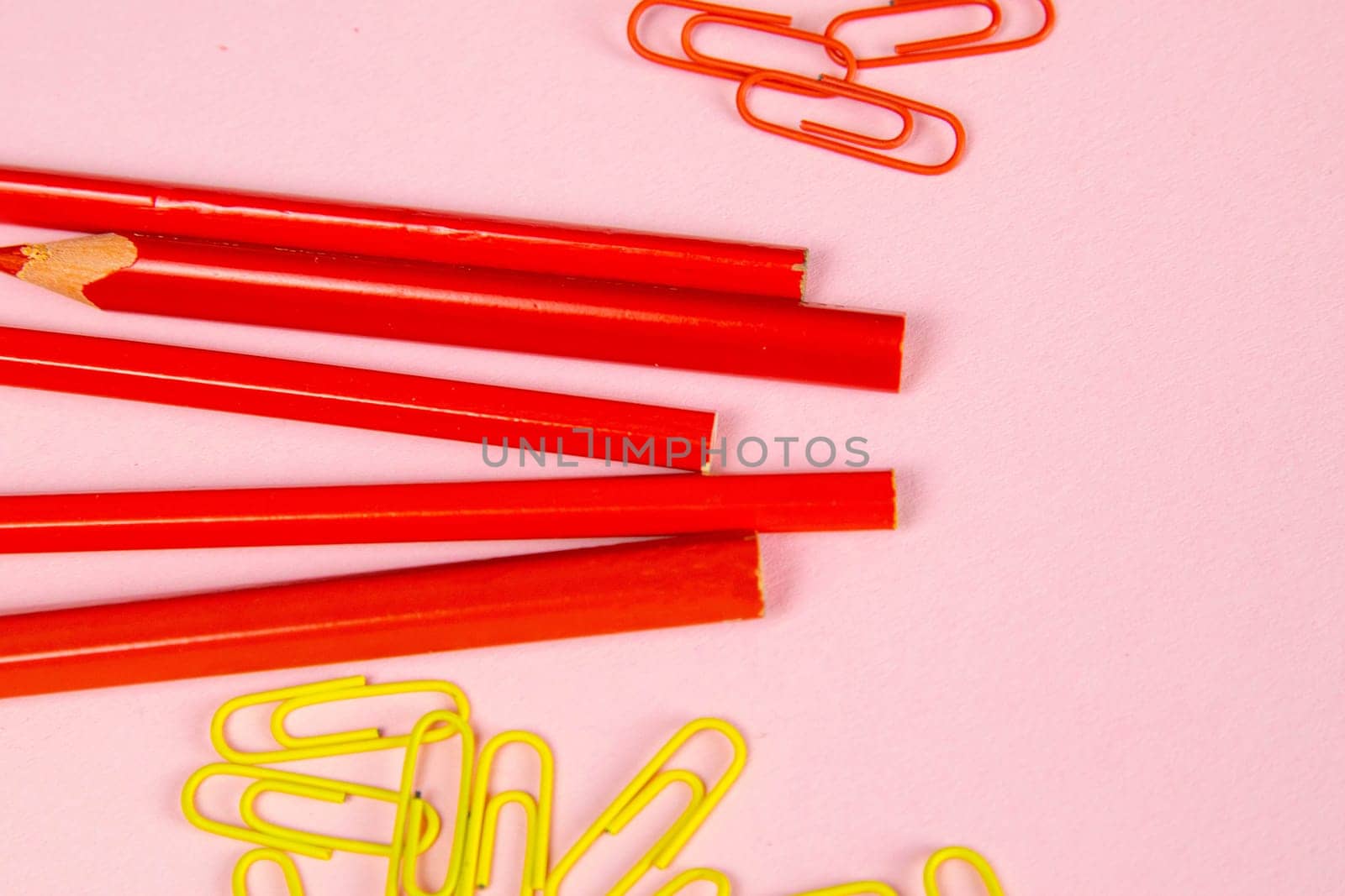 Multi-colored red pencils rulers, pens, pencils and scissors and stationery stand on a pink background.