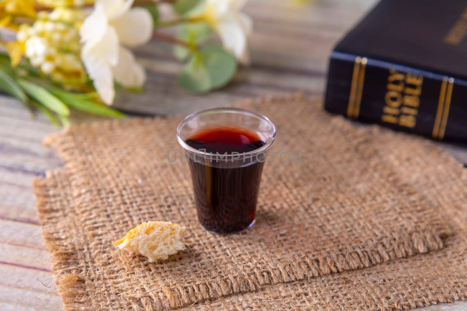 Taking communion concept - the wine and the bread symbols of Jesus Christ blood and body with Holy Bible. Easter Passover and Lord Supper concept Focus on glass.