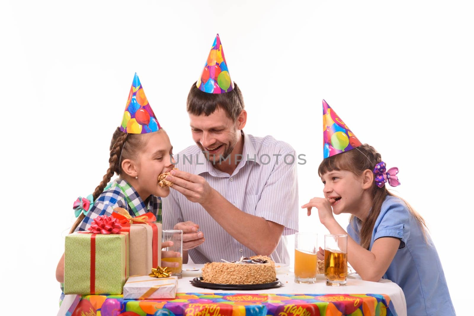 Dad and kids have fun eating cake at the festive table