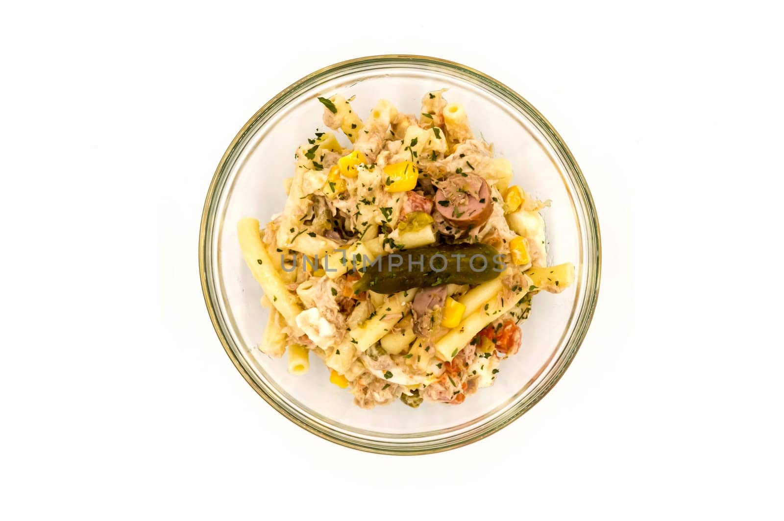 Pasta salad dish with corn, tuna and a pickle on a gray background