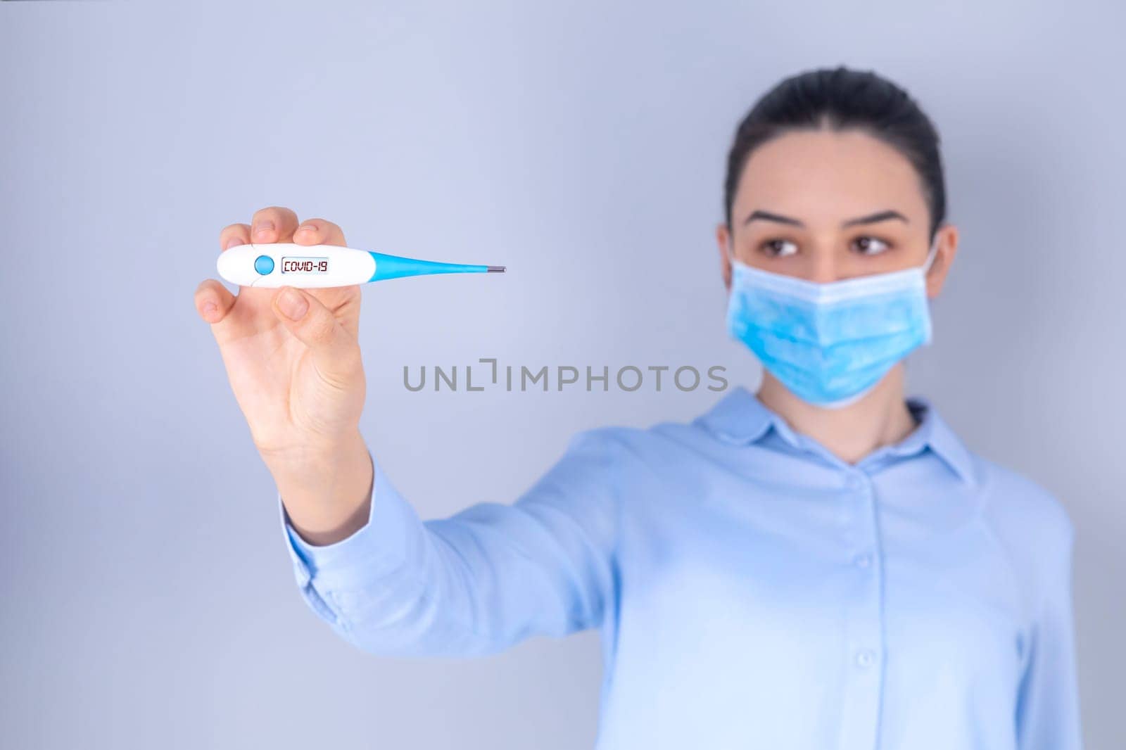 COVID-19 Pandemic Coronavirus Mask Fever Worry Girl Checking Temperature with Thermometer at Home Symptom of SARS-CoV-2. Girl with mask on face check fever one of symptoms of Coronavirus Disease 2019