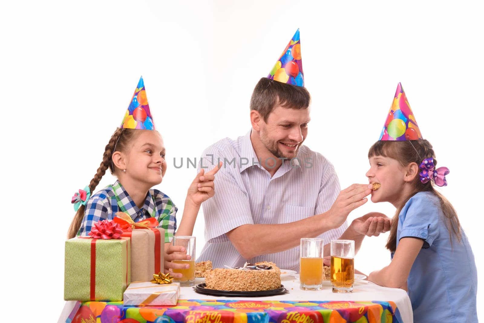 Dad fun stuffing a piece of cake in his daughter's mouth